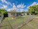 Home's front yard features mature tree, green lawn, and chain link fence at 2625 Williston Dr, Lakeland, FL 33801