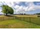 Large, grassy backyard features a black fence with views of trees and a golf course at 30505 Island Club Dr., Deer Island, FL 32778