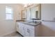 Bright bathroom boasts double sinks with granite countertops, framed mirrors, and modern vanity lighting at 30505 Island Club Dr., Deer Island, FL 32778