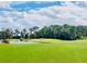 Scenic golf course view with a lush green fairway, pond, and mature trees under a partly cloudy sky at 30505 Island Club Dr., Deer Island, FL 32778