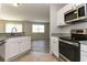 Modern kitchen with stainless steel appliances, granite countertops, white cabinets, and views of the living room at 2573 Carrington Ct, The Villages, FL 32162
