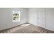 Standard bedroom with tan carpet, a closet door, and view of greenery outside at 607 Bay Leaf Dr, Poinciana, FL 34759