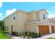 Side view of a well-maintained home with lush landscaping, a terracotta roof, and an attached two-car garage at 607 Bay Leaf Dr, Poinciana, FL 34759