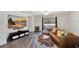 Cozy living room featuring a comfortable leather sofa, stylish rug, large TV, and sliding glass doors to the backyard at 329 W Aster Ct, Poinciana, FL 34759
