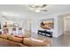Spacious living room with a large TV, leather sofa, modern rug, and an open view of the kitchen at 329 W Aster Ct, Poinciana, FL 34759