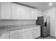 A kitchen with gray wood flooring, granite countertops, stainless steel appliances, and white cabinetry at 603 Bay Leaf Dr, Poinciana, FL 34759