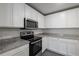 A kitchen with gray wood flooring, granite countertops, stainless steel appliances, and white cabinetry at 603 Bay Leaf Dr, Poinciana, FL 34759