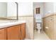 Well-lit bathroom features a large mirror, a single sink vanity, tiled walls, and a toilet with storage at 505 Millifiora Ln, Kissimmee, FL 34759
