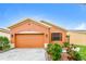 Charming single-story home featuring an orange stucco facade, two-car garage, and professionally landscaped front yard at 505 Millifiora Ln, Kissimmee, FL 34759