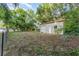 View of detached garage and partially wooded, grassy backyard with scattered leaves at 803 Mccranie Rd, Lakeland, FL 33809