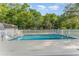 View of backyard swimming pool enclosed by white fence in grassy, partially wooded yard at 803 Mccranie Rd, Lakeland, FL 33809