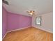A modest bedroom with wood-look floors, purple accent wall, and a single window at 9210 Lehall W Sq, Lakeland, FL 33810