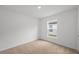 An empty bedroom provides neutral carpeting and a window overlooking the green outdoors at 2214 Pecos Ct, Poinciana, FL 34759