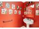 This eye-catching red half-bathroom features an artistically themed wall at 4014 Gallagher Loop, Casselberry, FL 32707