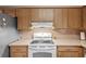 Functional kitchen with a white stove, range hood, and wooden cabinetry at 4915 Whiteoak E Dr, Lakeland, FL 33813