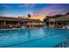 Large community pool with comfortable lounge chairs under blue umbrellas, under a beautiful evening sky at 6237 Sw 96Th Pl, Ocala, FL 34476