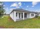 Exterior rear view of home with a covered patio, lush grass, and professionally installed landscaping at 5950 Bristle Oak St, Mount Dora, FL 32757
