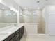 Bathroom featuring dual sinks, a glass-enclosed shower, and tile walls and floors at 5950 Bristle Oak St, Mount Dora, FL 32757