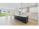Open-concept kitchen boasts a large island, white cabinets, modern appliances, and sleek hardwood floors at 5950 Bristle Oak St, Mount Dora, FL 32757