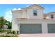 Exterior shot showcasing the two-story townhome with a two-car garage and brick-paved driveway at 596 Bay Leaf Dr, Poinciana, FL 34759