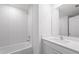 Bathroom featuring modern white tiled walls, shower-tub combo, and sink with white cabinets at 639 Gila Dr, Poinciana, FL 34759
