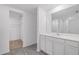 Bathroom featuring gray vinyl floors, white cabinets and countertops, walk-in closet, and large mirror at 639 Gila Dr, Poinciana, FL 34759