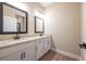 Bathroom with double sink vanity, granite countertop, modern fixtures, and wood floor at 7696 Somersworth Dr, Kissimmee, FL 34747
