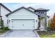 A two-car garage with a light blue door and a paver driveway is the focal point of the exterior shot at 7696 Somersworth Dr, Kissimmee, FL 34747