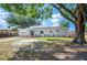 The front exterior of a charming single-story home featuring manicured lawn, new landscaping, and a shade tree at 1037 Waynesville Ave, Lakeland, FL 33801