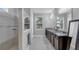 Bright bathroom featuring double sinks, dark wood cabinets, a tiled shower and window at 7071 Spring Park Dr, Winter Garden, FL 34787