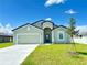 Charming single-story home featuring a two-car garage and a beautifully landscaped front yard on a sunny day at 385 Begonia Ct, Poinciana, FL 34759