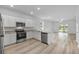 Open kitchen with stainless appliances, granite counters, and wood-look flooring at 385 Begonia Ct, Poinciana, FL 34759