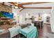 Charming living room featuring a brick fireplace, wood beams, hardwood floors, and an open flow to the modern kitchen at 132 Margate Mews, Longwood, FL 32779