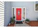 Close up of the bright red front door framed by sidelights and decorative planters at 4133 Staffordshire Dr, Lakeland, FL 33809