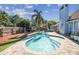 A sparkling in-ground pool is surrounded by a brick patio and lush landscaping at 4133 Staffordshire Dr, Lakeland, FL 33809