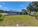 View of home's backyard with mature trees, lush lawn and a white picket fence at 5349 Hidden Oaks Dr, Lakeland, FL 33811