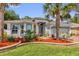 Charming home exterior with lush landscaping, including palm trees and colorful flowerbeds enhancing curb appeal at 10367 Addison Shore Way, Oxford, FL 34484