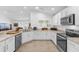 Well-lit kitchen with white cabinetry, stainless steel appliances, and a view into the living area at 10367 Addison Shore Way, Oxford, FL 34484