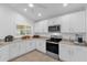 Well-lit kitchen features white cabinets, stainless-steel appliances, and tiled floor at 10367 Addison Shore Way, Oxford, FL 34484
