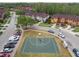 This aerial view shows a community basketball court surrounded by townhomes and lush trees in the neighborhood at 6109 Apollos Corner Way, Orlando, FL 32829