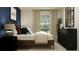 Bright bedroom features a dark-wood bed frame, a large window with beige curtains, and a black dresser with a mirror at 1313 Acorn Meadow Loop, Eustis, FL 32726