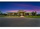 Attractive exterior nighttime view of the community clubhouse with palm trees, landscaping, and a paved driveway at 2991 Wood Duck Dr, Polk City, FL 33868