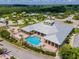 Aerial view of a clubhouse with a pool, surrounded by lush greenery, with tiki bars and a play area in the distance at 2991 Wood Duck Dr, Polk City, FL 33868