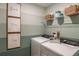 The laundry room includes a washer and dryer, framed prints, shelving with baskets and storage container at 3799 King Hill Dr, Haines City, FL 33844