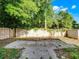 An open backyard featuring a concrete tiled patio area, framed by a wooden fence and lush greenery at 156 Oak Grove Rd, Winter Park, FL 32789