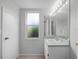 Simple, well-lit bathroom featuring a vanity, mirror, and a window providing natural light at 156 Oak Grove Rd, Winter Park, FL 32789