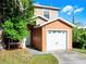 Two-story tan home with a single car garage and green lawn at 156 Oak Grove Rd, Winter Park, FL 32789