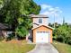 Two-story tan home with a single car garage and mature shade trees at 156 Oak Grove Rd, Winter Park, FL 32789