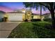 Inviting two-story home featuring a manicured lawn, mature tree, and two-car garage at 440 Langham Dr, Davenport, FL 33897