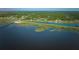 A stunning aerial view of a serene lake surrounded by lush green trees and a clear blue sky at 6589 Banyan Dr, Indian Lake Estates, FL 33855